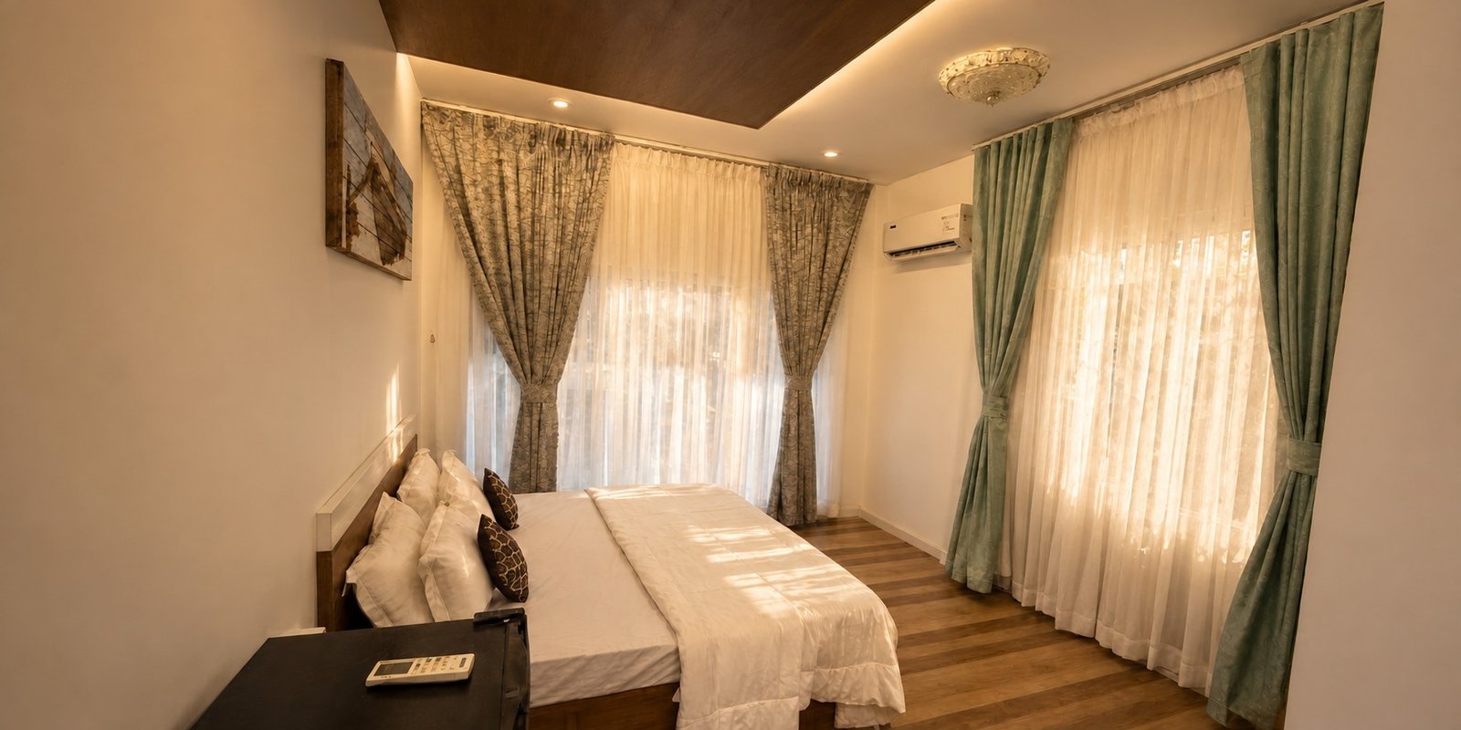 Sunlit Mayooram bedroom with a double bed and tall curtains